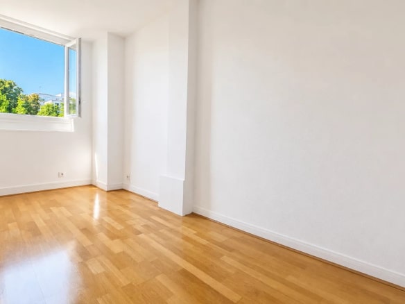 Interior of a renovated apartment with parquet flooring, open window and natural light in Meudon.