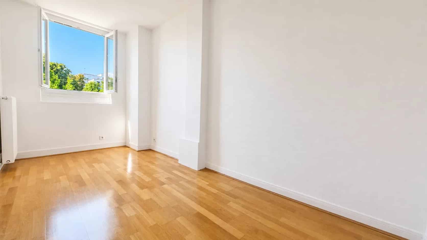 Interior of a renovated apartment with parquet flooring, open window and natural light in Meudon.