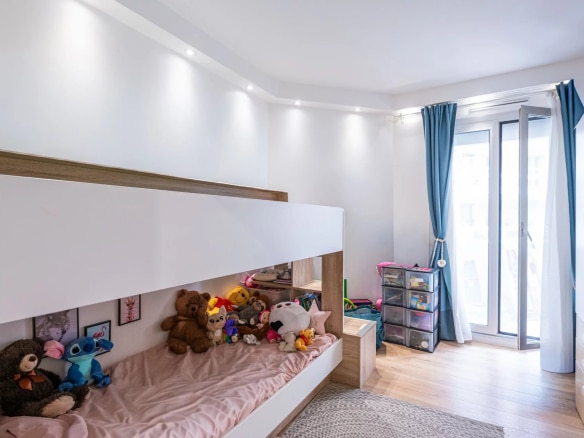 Chambre d'appartement avec lit superposé et jouets, accès à un balcon.