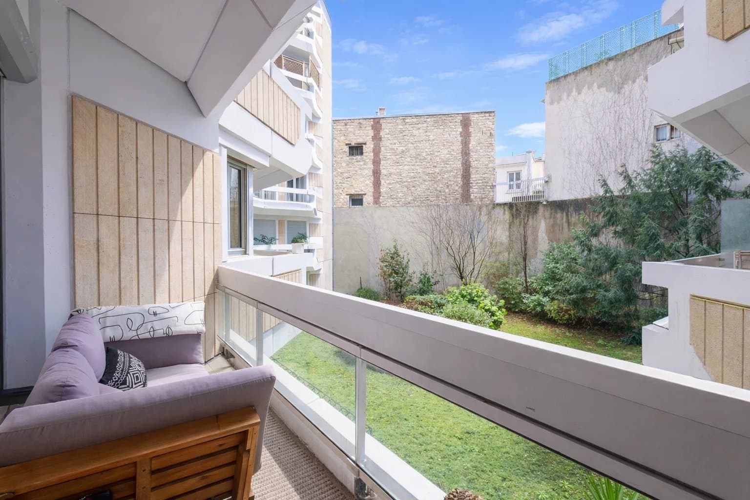 Balcon d'un appartement à Neuilly-sur-Seine avec vue sur un jardin intérieur.