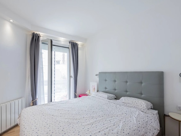 Chambre d'un appartement moderne avec lit double et accès à un balcon.