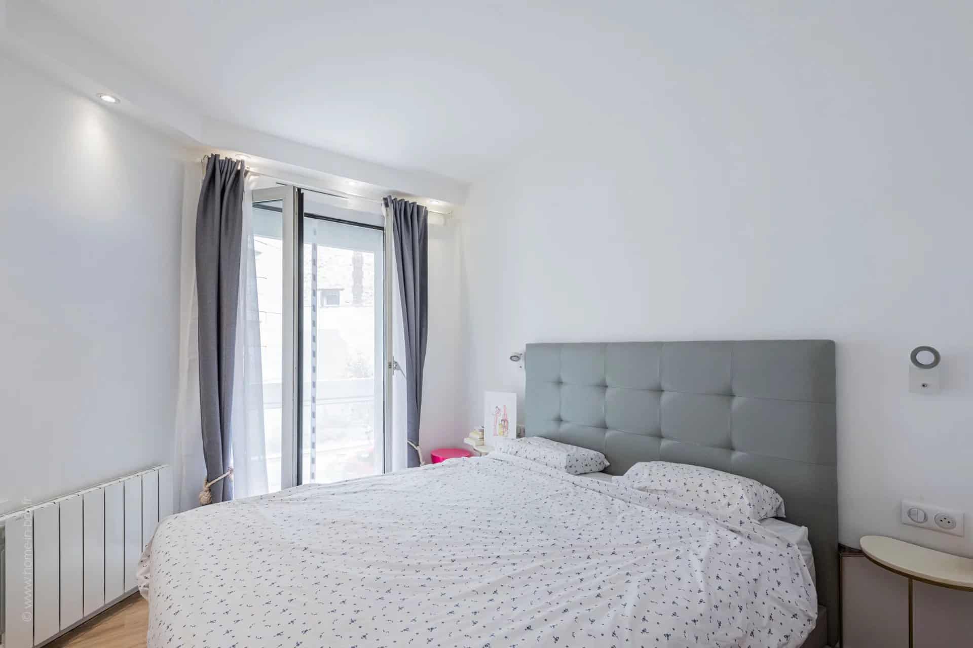 Chambre d'un appartement moderne avec lit double et accès à un balcon.