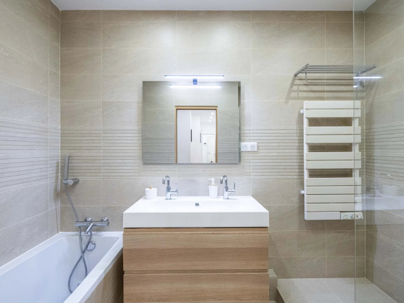 Salle de bain moderne avec baignoire, lavabo et miroir, décor beige.