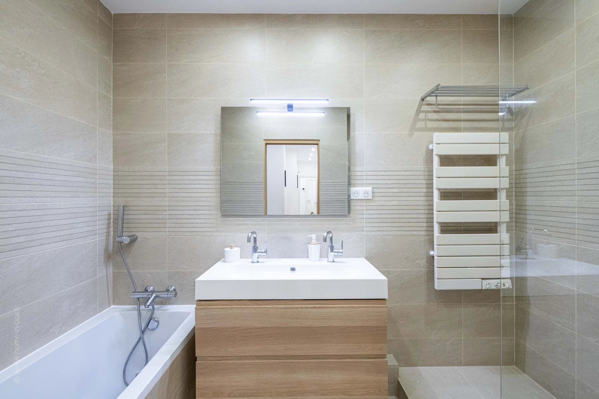 Salle de bain moderne avec baignoire, lavabo et miroir, décor beige.