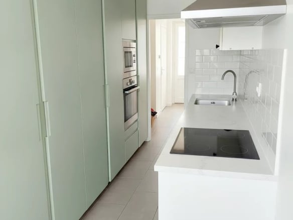 Cuisine moderne d'un duplex à Courbevoie avec des meubles verts et des appareils électroménagers intégrés.