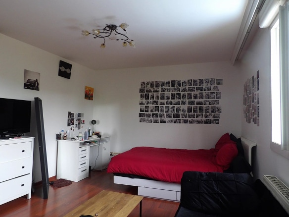 Chambre d'une maison individuelle avec lit, bureau et décorations murales.