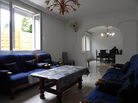 Intérieur d'une grande maison individuelle avec salon et salle à manger, meubles en bois et décoration simple.