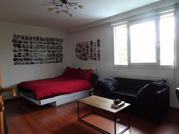 Chambre avec lit simple, canapé et murs décorés de photos.