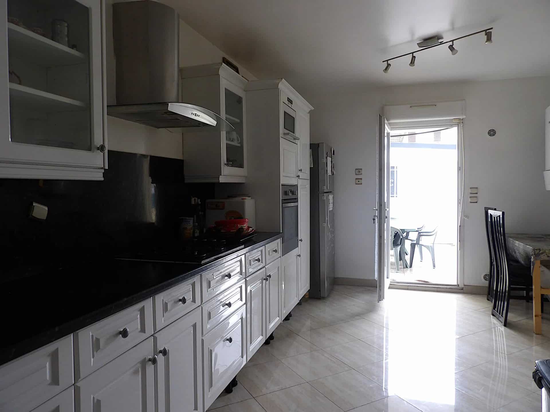 Cuisine moderne avec accès extérieur Intérieur d'une cuisine moderne avec meubles blancs et accès à une terrasse.