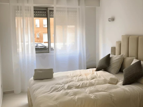 Chambre lumineuse avec lit double et fenêtre, décorée de manière moderne.