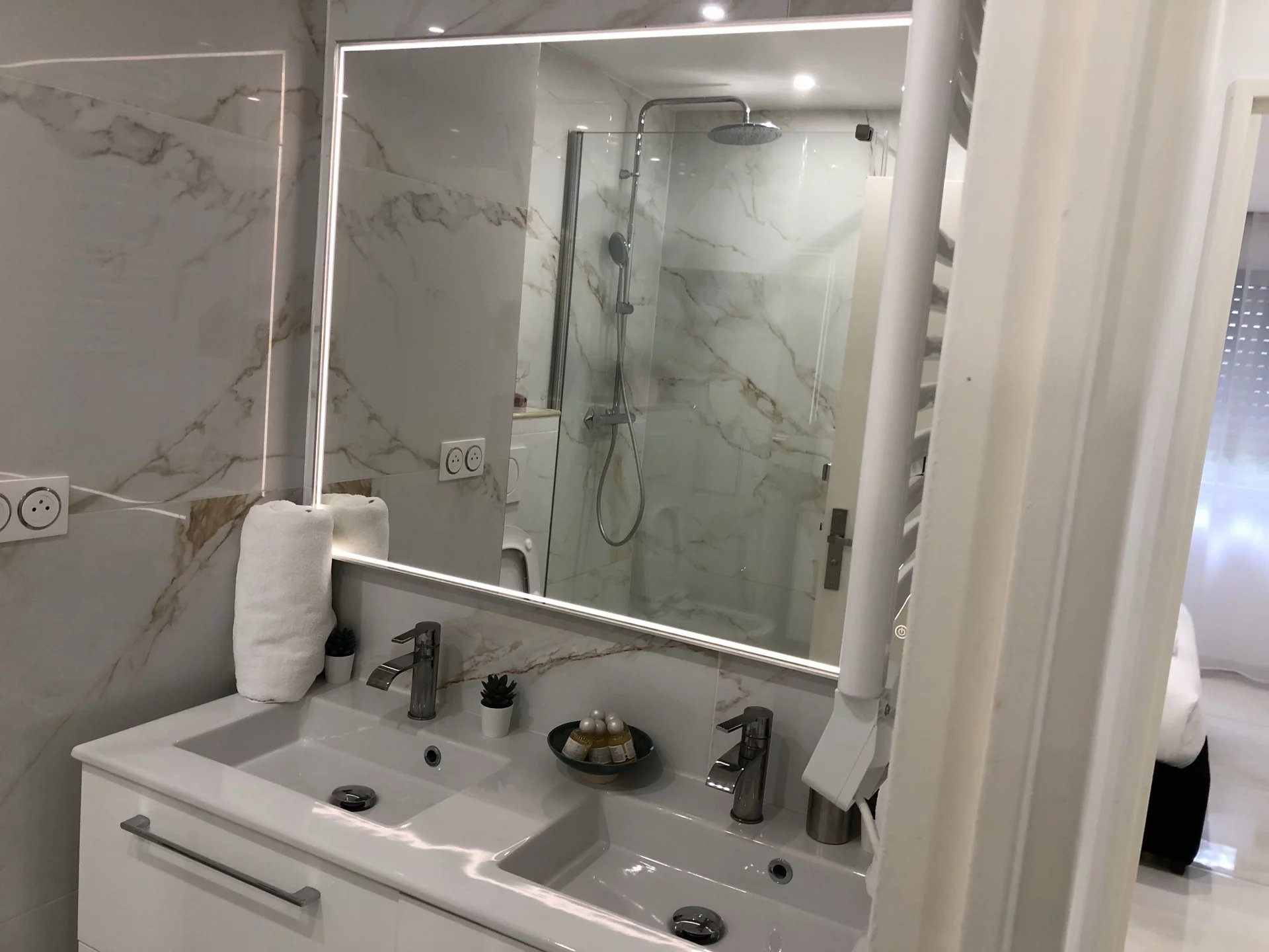 Salle de bain d’un appartement rénové Salle de bain moderne avec miroir éclairé et douche à l'italienne