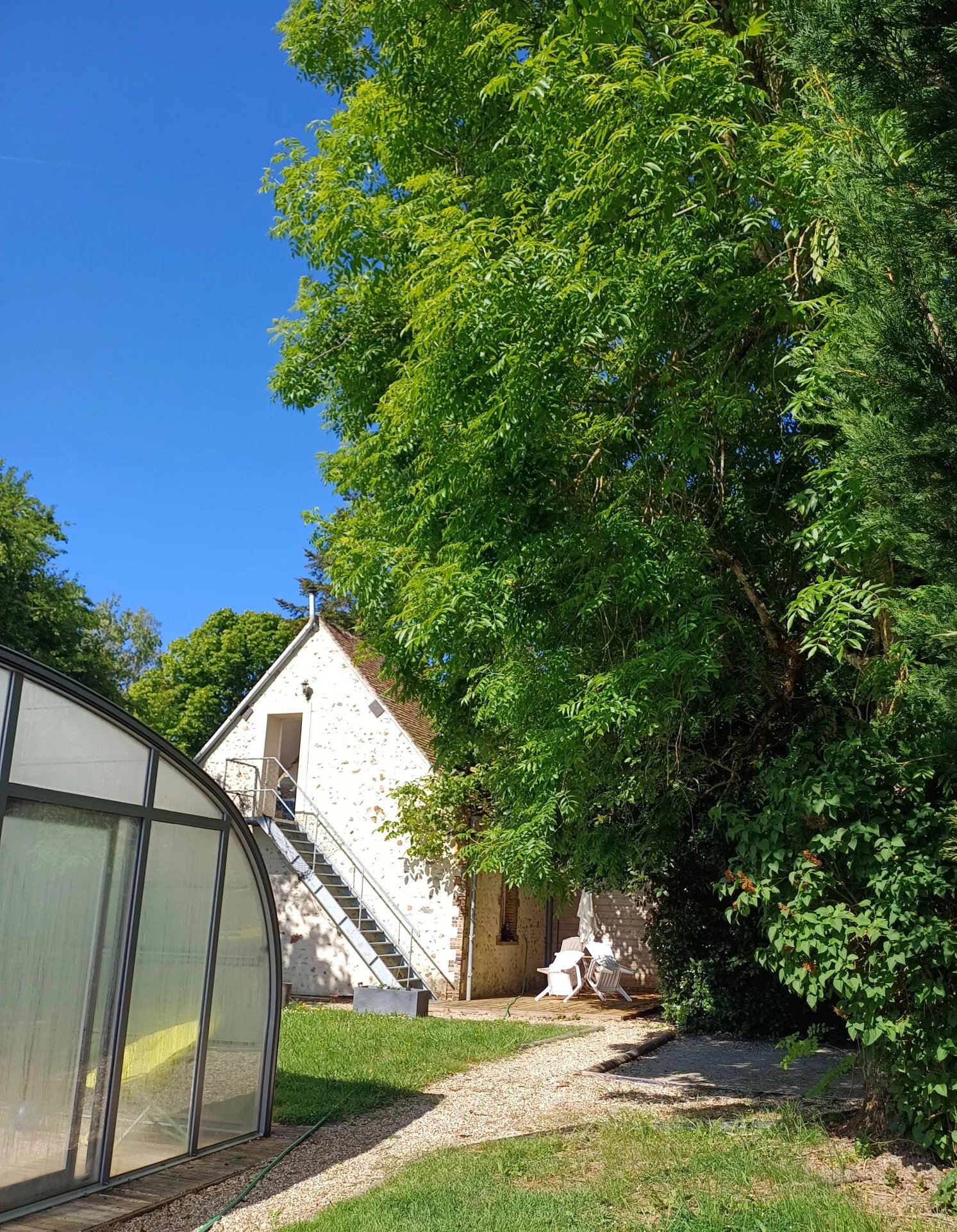 Bâtiment en pierre avec un escalier, entouré d'arbres dans un parc naturel.