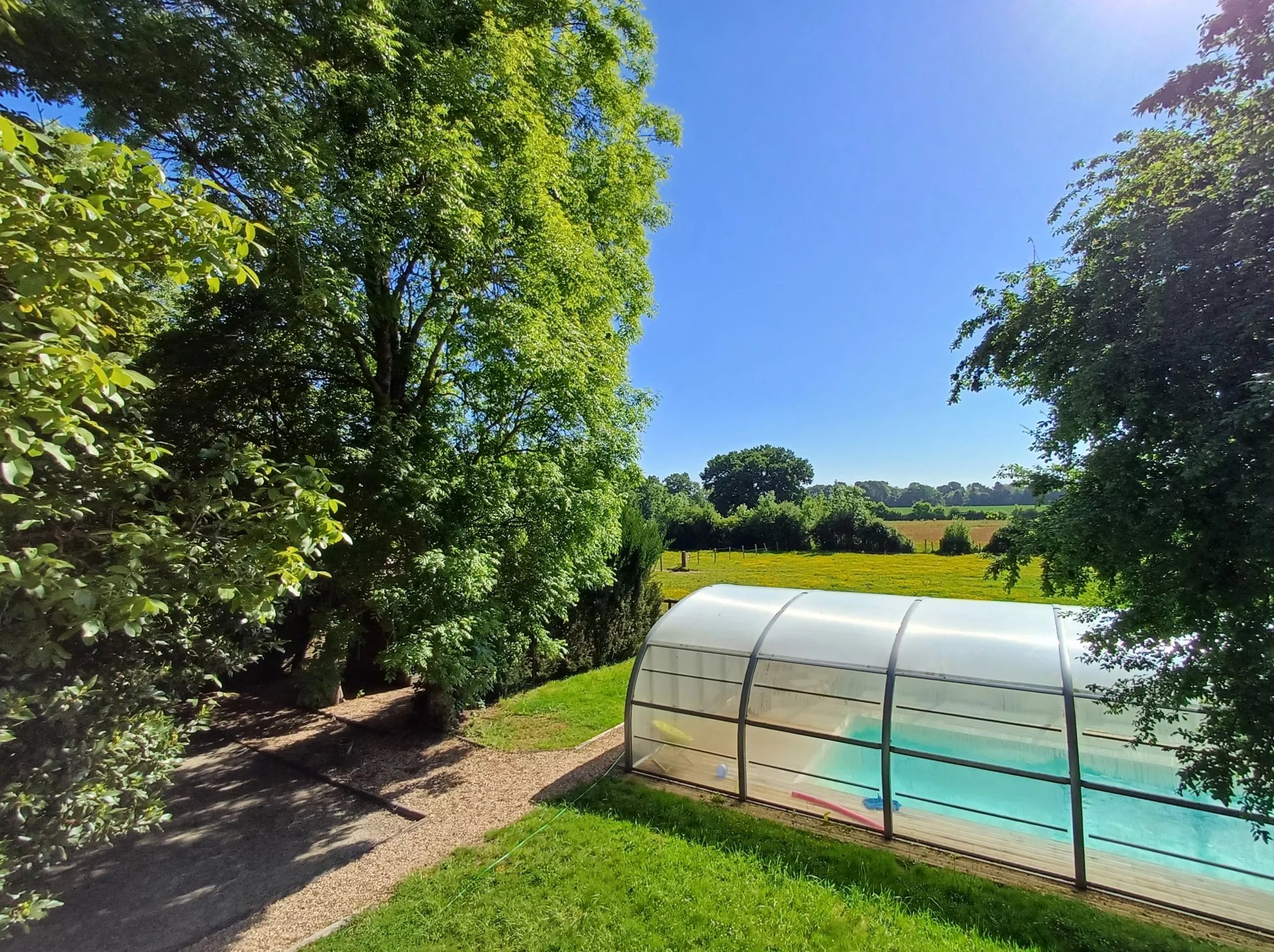 Vue d'un espace extérieur avec piscine couverte et verdure, Parc Naturel Régional du Perche.