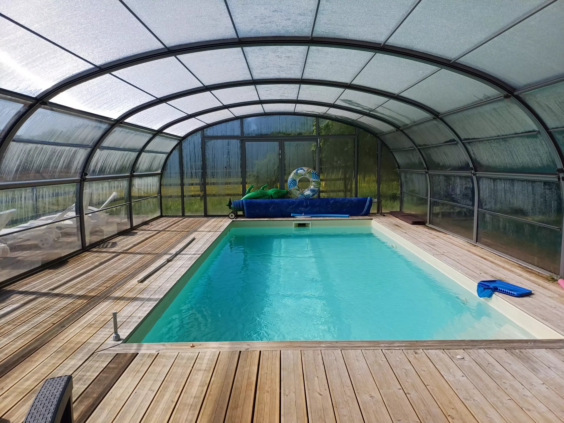 Piscine intérieure couverte avec un espace en bois autour, dans un ensemble immobilier.