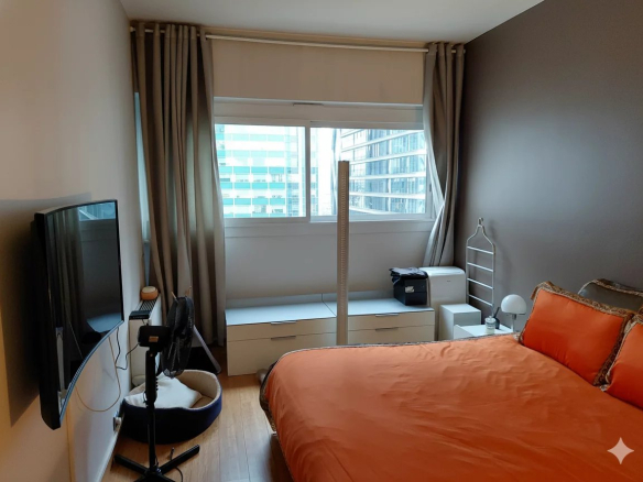 Chambre d'un duplex à Courbevoie avec lit orange et fenêtre donnant sur des immeubles modernes.