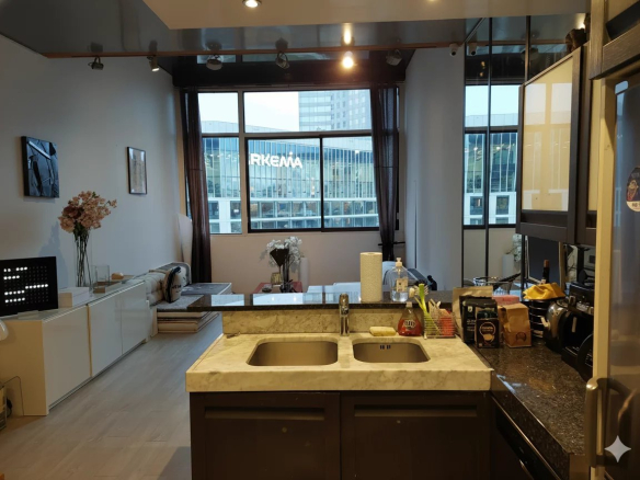 Intérieur d'un duplex lumineux avec cuisine ouverte et vue sur des bâtiments modernes.