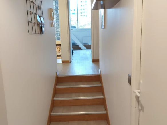 Intérieur d'un duplex à Courbevoie avec un couloir et des escaliers en bois.