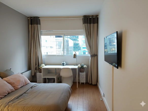 Chambre d'un duplex lumineux à Courbevoie avec vue sur des immeubles modernes.