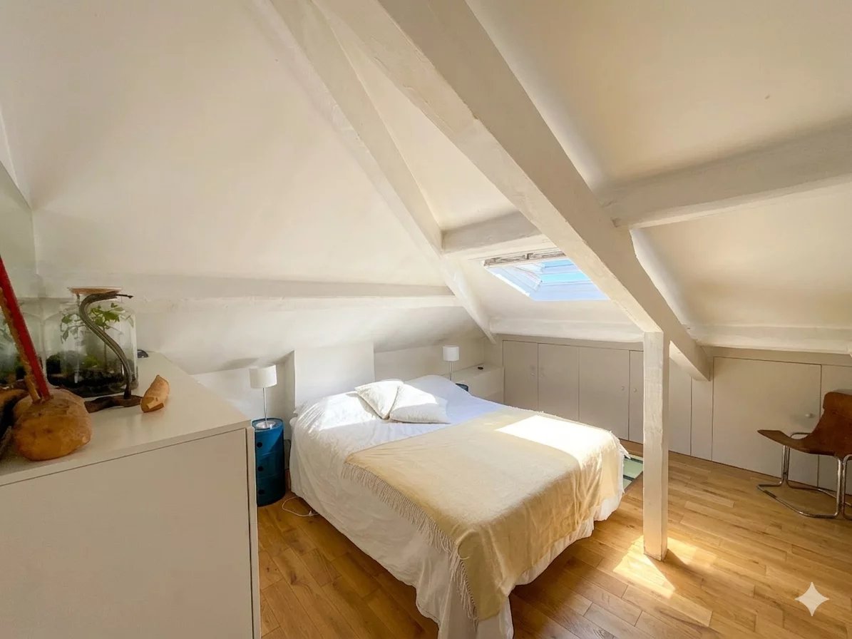 Chambre d’un duplex à Paris 6ème Chambre d'un duplex lumineux avec poutres apparentes et lit double.