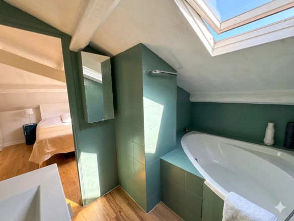 Salle de bain d'un duplex à Paris avec baignoire et fenêtre de toit.