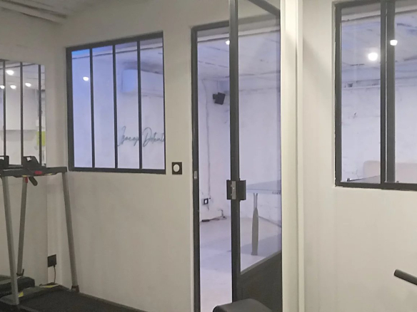 Intérieur d'un espace de bureau avec des fenêtres en verre et des équipements de fitness.