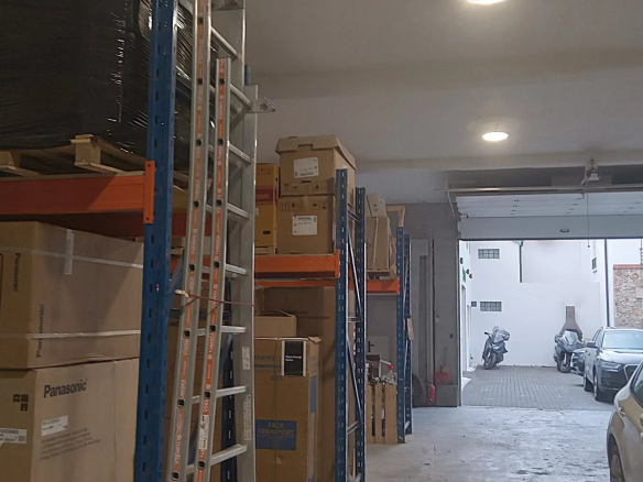Intérieur d'un entrepôt avec des étagères chargées de cartons et un accès à l'extérieur à Choisy-le-Roi.