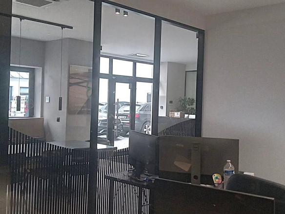 Intérieur d'un bureau moderne avec des murs en verre et un espace de travail.