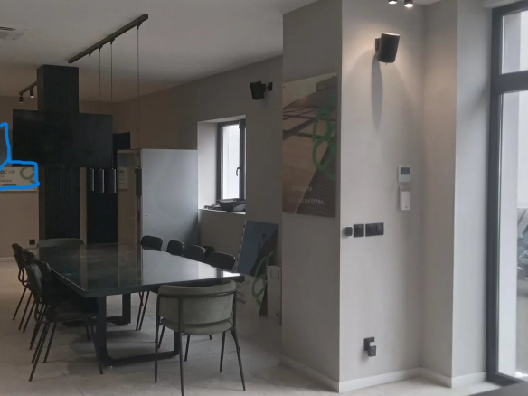 Intérieur d'un espace de bureaux moderne avec table et chaises, fenêtre et moto visible à l'extérieur.