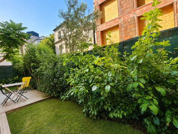Jardin privatif arboré avec mobilier de jardin dans un appartement à Paris 18ème.