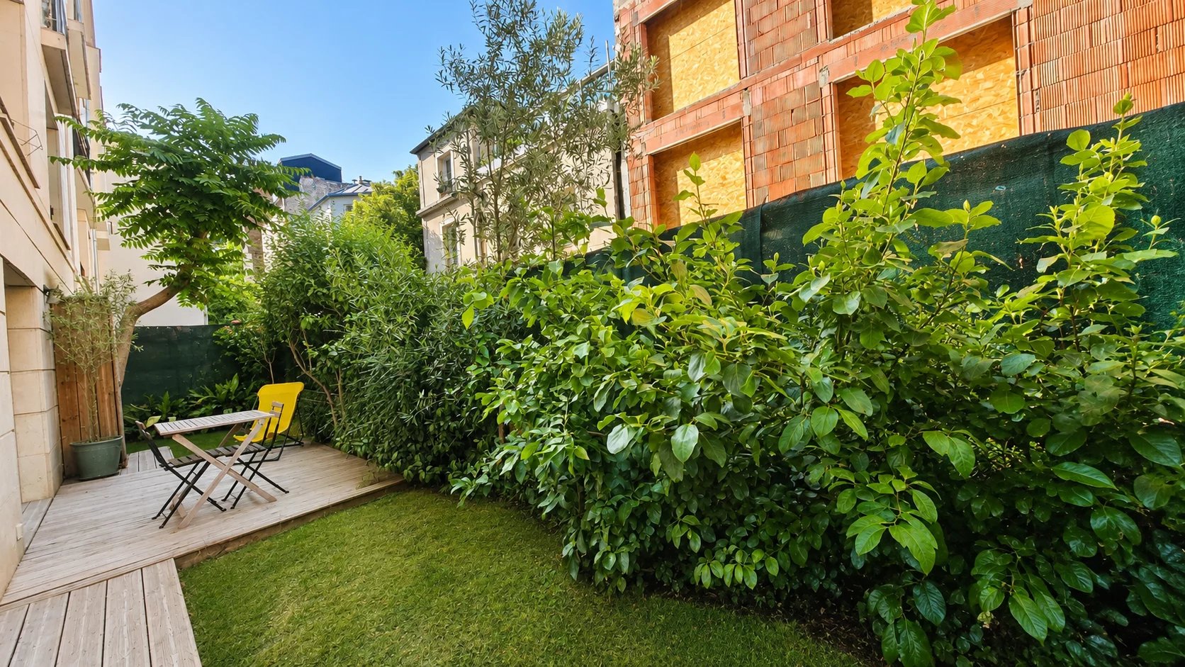 Jardin privatif arboré avec mobilier de jardin dans un appartement à Paris 18ème.