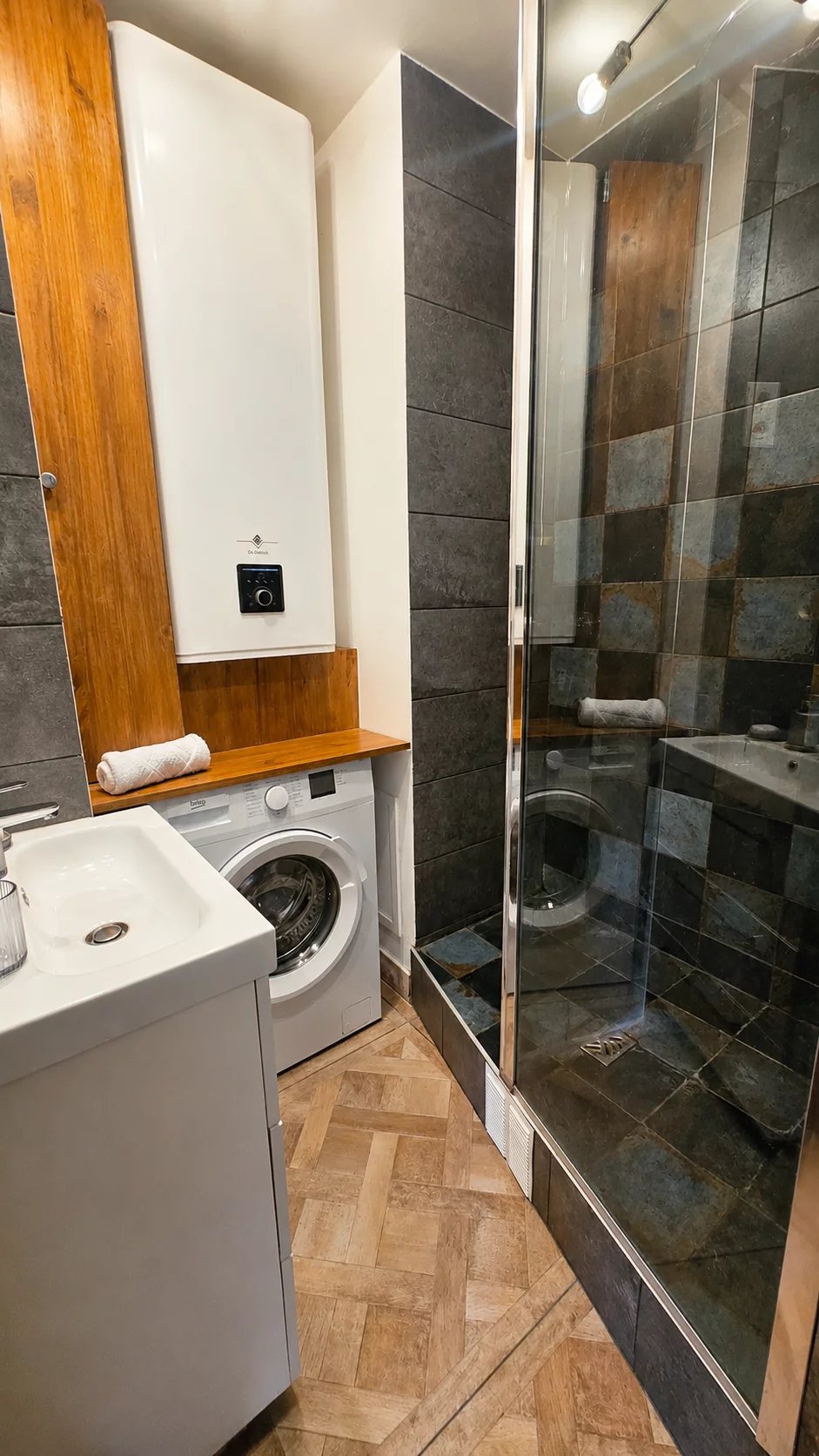 Salle de bain rénovée avec douche, lave-linge et meuble vasque.
