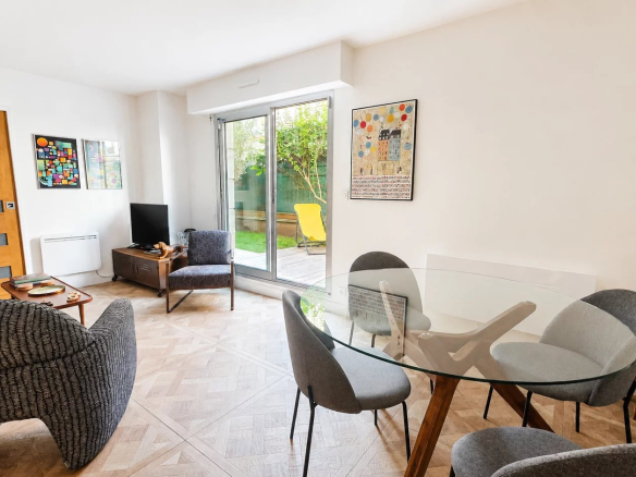 Intérieur d'un appartement rénové avec salon, salle à manger et accès à un jardin privatif.