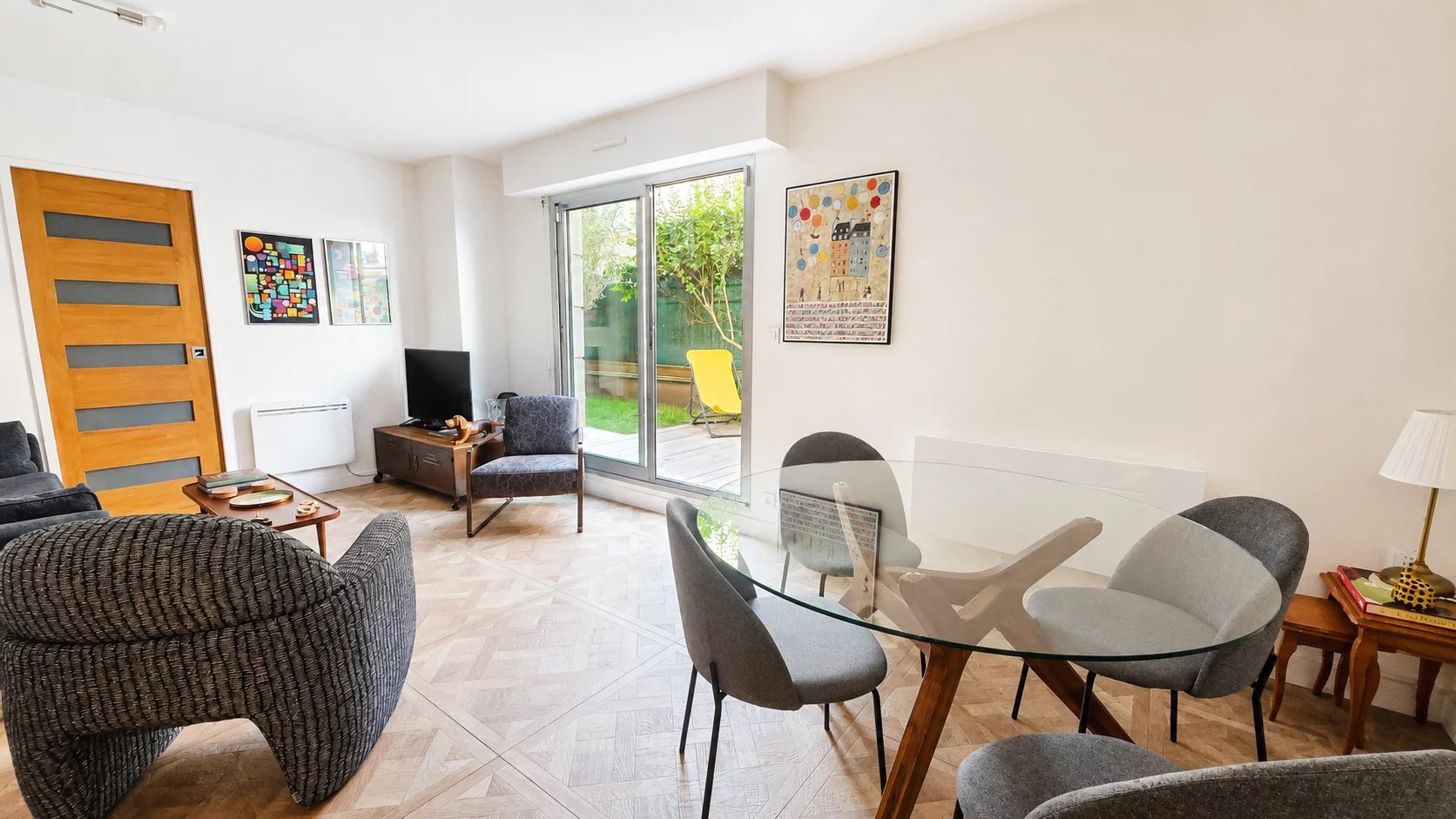Intérieur d'un appartement rénové avec salon, salle à manger et accès à un jardin privatif.