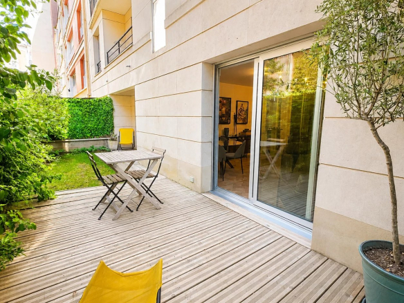 Terrasse en bois avec mobilier de jardin et jardin privatif arboré.