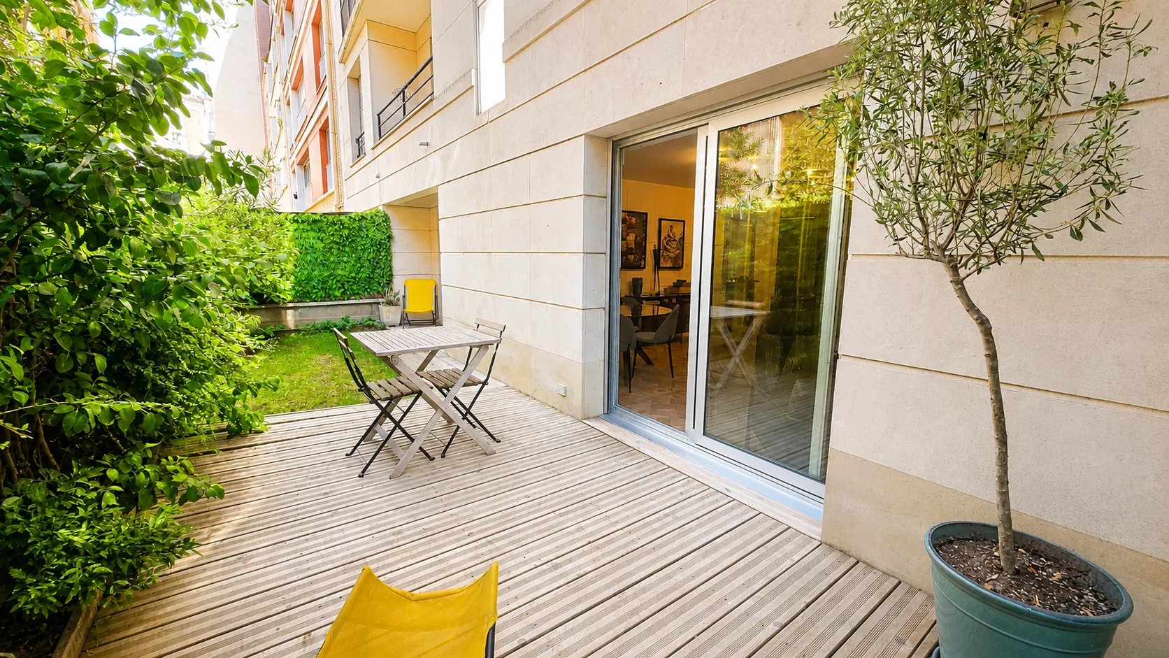 Terrasse en bois avec mobilier de jardin et jardin privatif arboré.