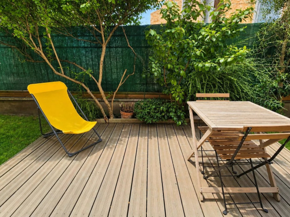 Jardin privatif arboré avec mobilier en bois et chaise longue, situé à Paris 18ème.