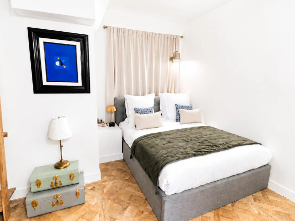 Chambre d'un appartement rénové avec un lit double et des éléments de décoration moderne.