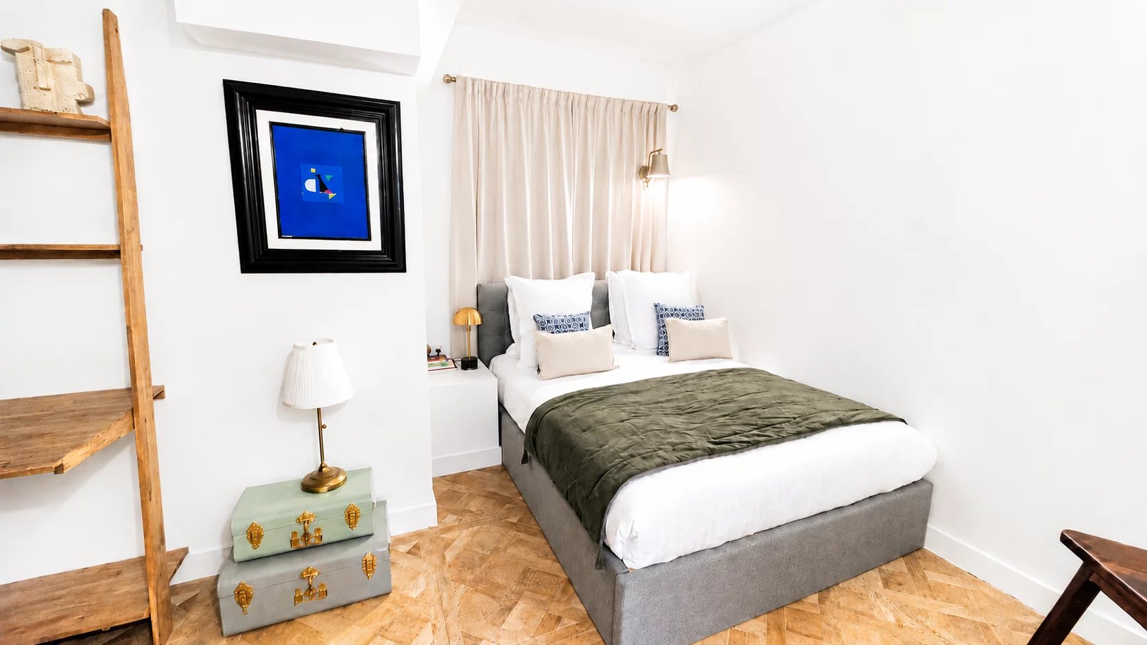 Chambre d'un appartement rénové avec un lit double et des éléments de décoration moderne.