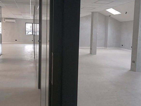 Interior of an empty office building complex with concrete walls and large windows.