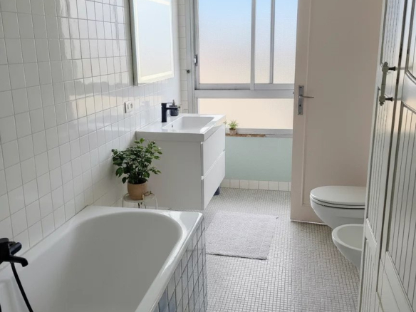 Salle de bain moderne avec baignoire, lavabo et fenêtre à Courbevoie.