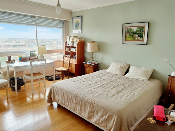 Chambre d'un duplex à Courbevoie avec vue sur Paris, lit, bureau et fenêtre.