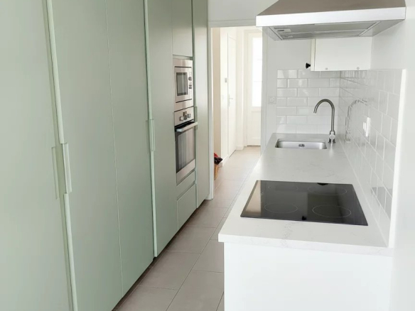 Cuisine moderne d'un duplex à Courbevoie avec des meubles de rangement verts et des appareils électroménagers intégrés.