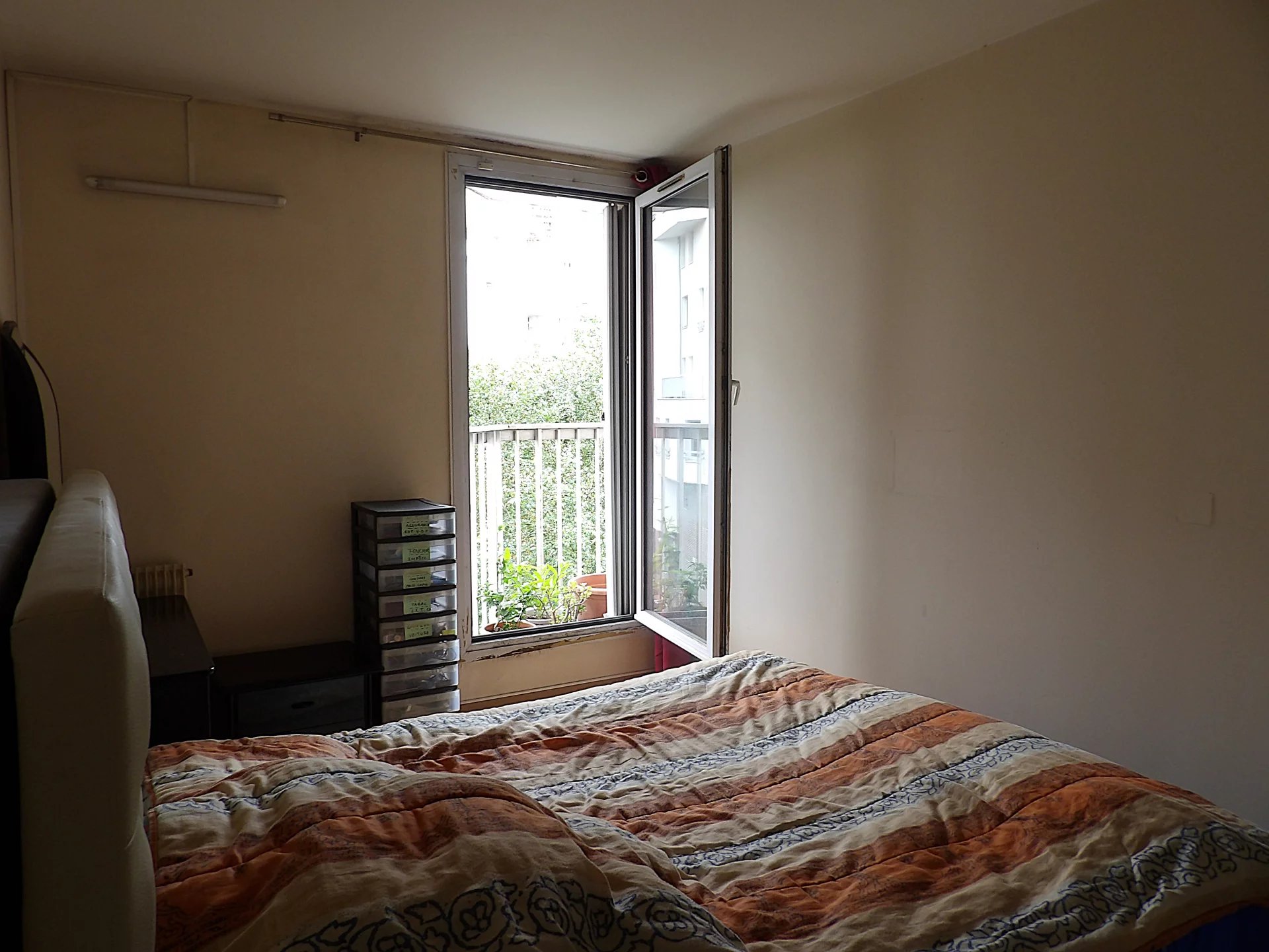 Chambre d’appartement à Paris 13ème Chambre d'un appartement avec un lit et une fenêtre donnant sur un balcon.