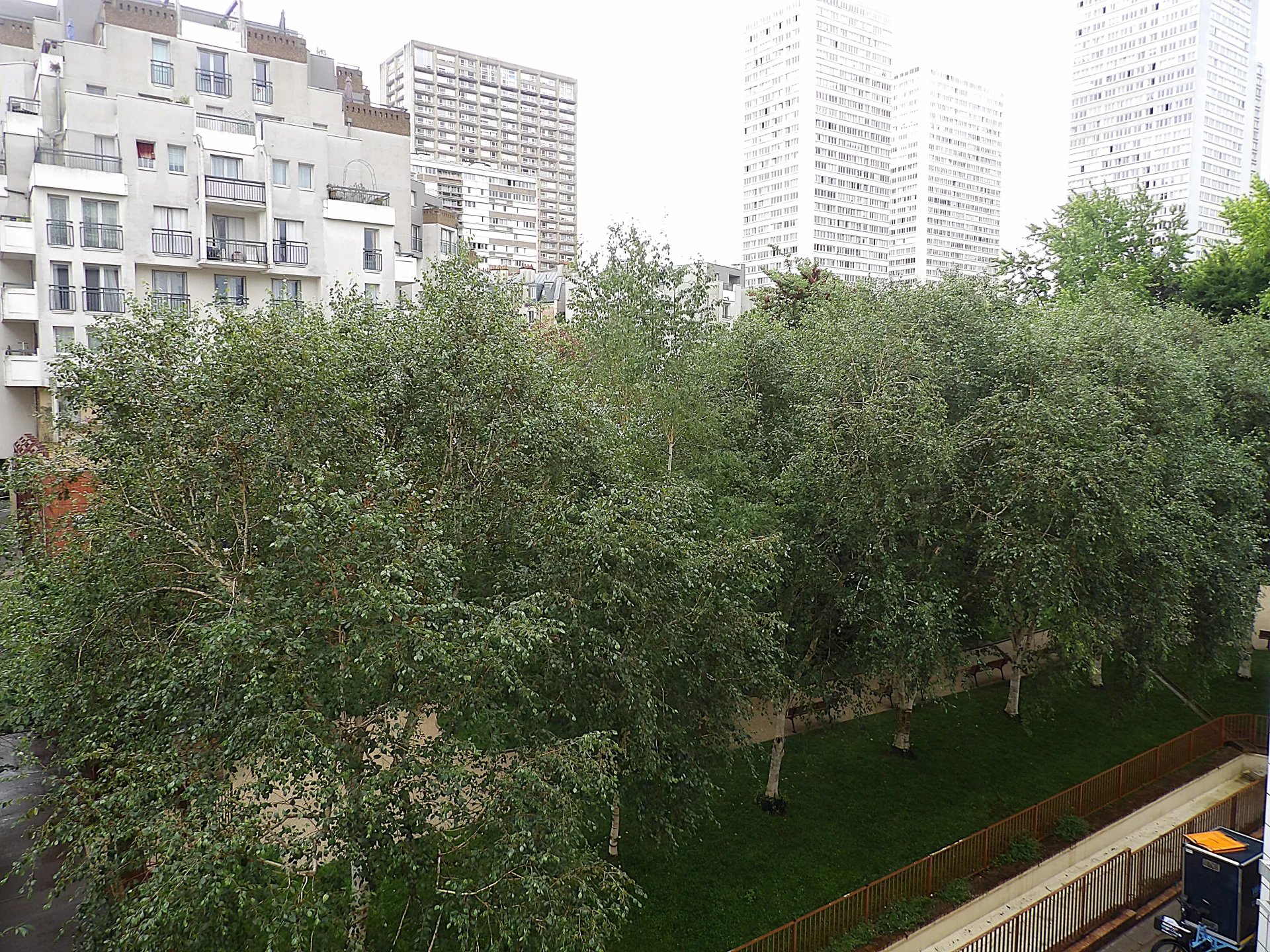 Espace vert à Paris 13ème Vue d'un espace vert avec des arbres et des bâtiments en arrière-plan à Paris 13ème.