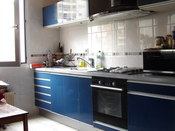 Cuisine d'un grand appartement à Paris 13ème avec des meubles bleus et des équipements modernes.