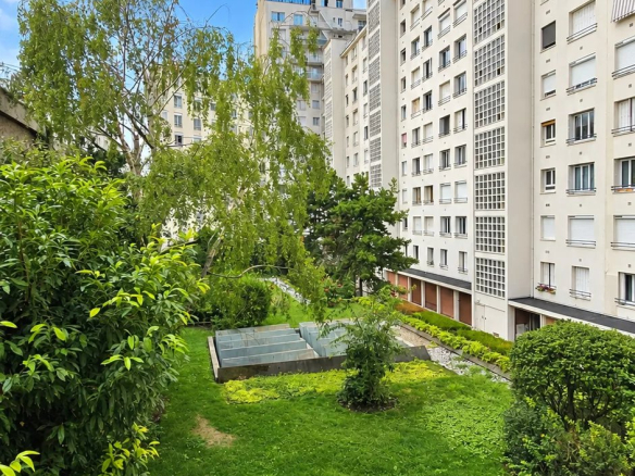 Vue d'un jardin et d'immeubles à Boulogne-Billancourt, avec verdure et ciel bleu.