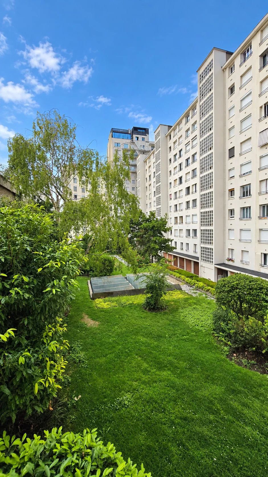 Jardin à Boulogne-Billancourt Vue d'un jardin et d'immeubles à Boulogne-Billancourt, avec verdure et ciel bleu.