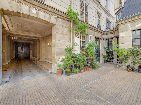 Entrée d'un immeuble en pierre de taille avec cour intérieure et plantes à Paris 17ème.