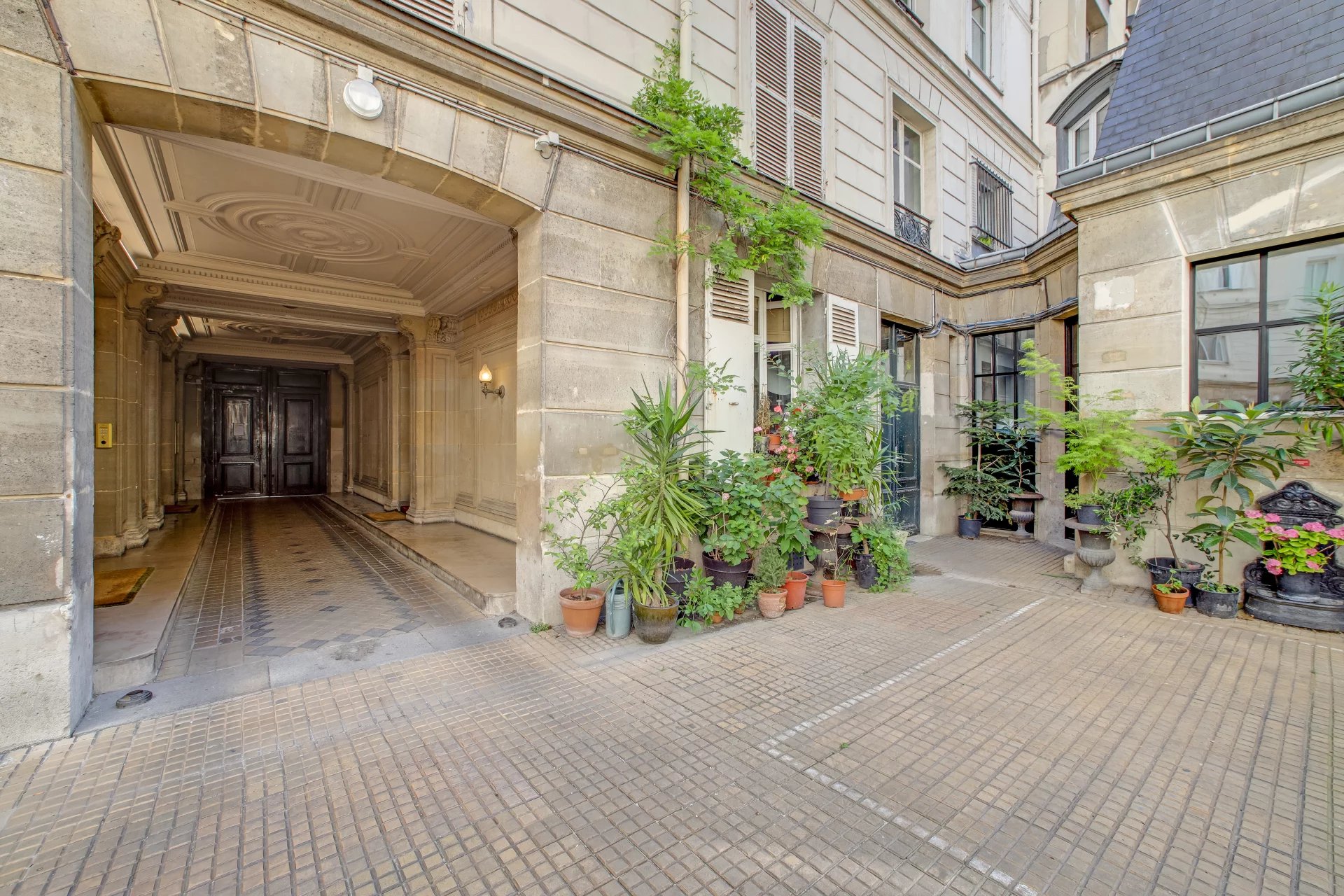 Entrée d’immeuble à Paris 17ème Entrée d'un immeuble en pierre de taille avec cour intérieure et plantes à Paris 17ème.