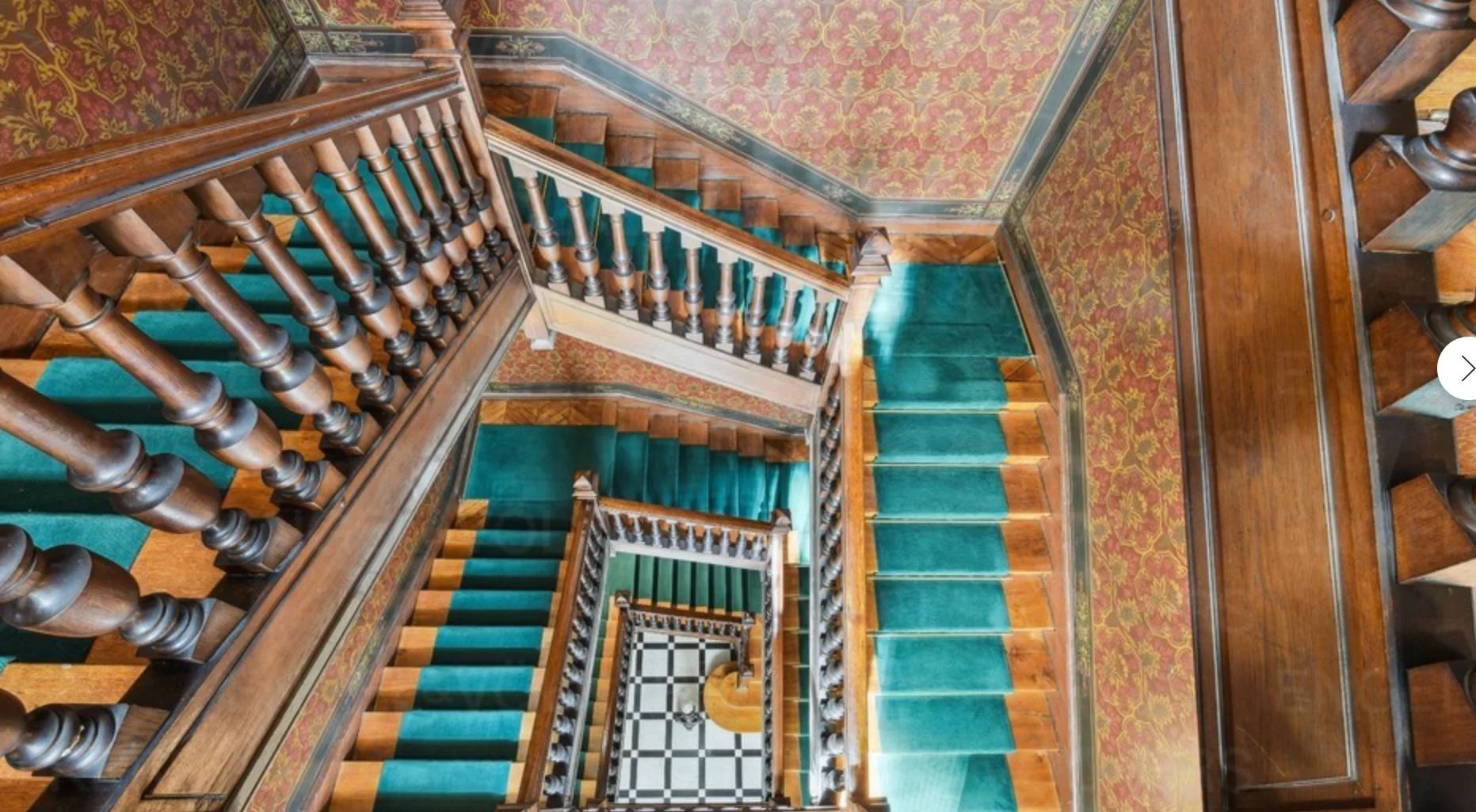 Escalier d’immeuble ancien à Paris 17ème Escalier en bois avec rampe, moquette verte et murs décorés dans un immeuble ancien à Paris 17ème.